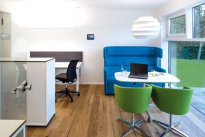 Ein heller Home-Office-Raum mit mobilem Arbeitstisch, großflächiger Wandverglasung und Oberlichtfenstern von Regnauer.