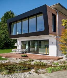 Eine moderne Villa in Seitenansicht mit klaren Linien, großzügigen Fensterflächen und eleganter Fassadengestaltung von Regnauer.