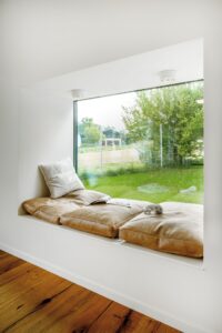 Ein helles Sitzfenster mit gepolstertem Ledersitz und Decken‑Spots, das zum Verweilen einlädt von Regnauer.