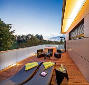 Eine moderne Villa mit überdachter Terrasse und Dachterrasse bzw. Balkon mit Außendusche, Liegen und einem Whirlpool von Regnauer.
