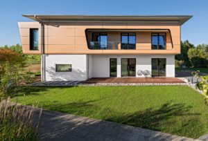 Ein modernes Haus in Seitenansicht mit überdachter Terrasse, bodentiefen Glaselementen, Loggia mit Glasgeländer, auskragendem Dachvorsprung und Holzoptik-Fassadenelementen von Regnauer.
