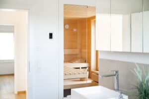 Ein Badezimmer mit Blick auf die Sauna mit Holziegen - eine private Wellness‑Oase von Regnauer Hausbau.