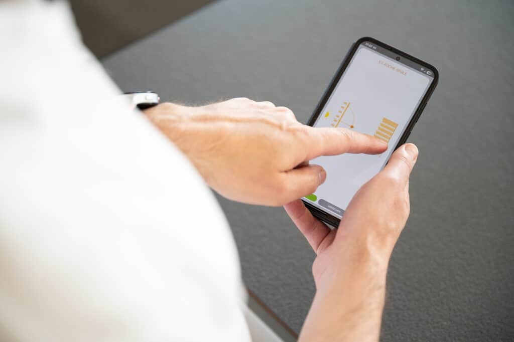 Reganuer Fertighaus zeigt ein Smartphone mit einer App mit der die Beschattung der Räume gesteuert werden kann.