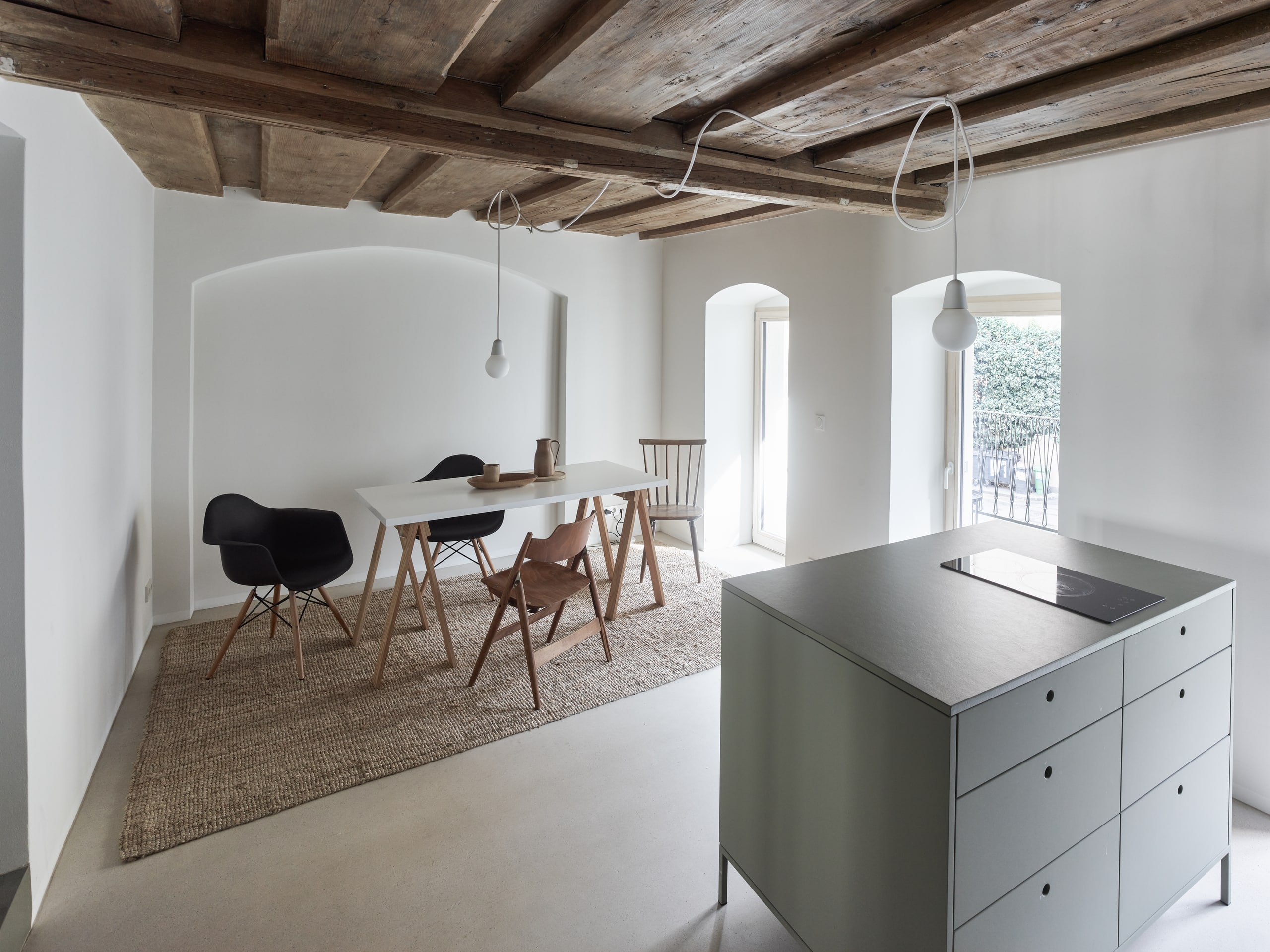 RÖFIX präsentiert eine Wohnküche mit Essbereich das Referenzprojekt Stadthaus Lederergasse mit Holzdecke, einen verbauten Gewölbebogen und Terrassentür.