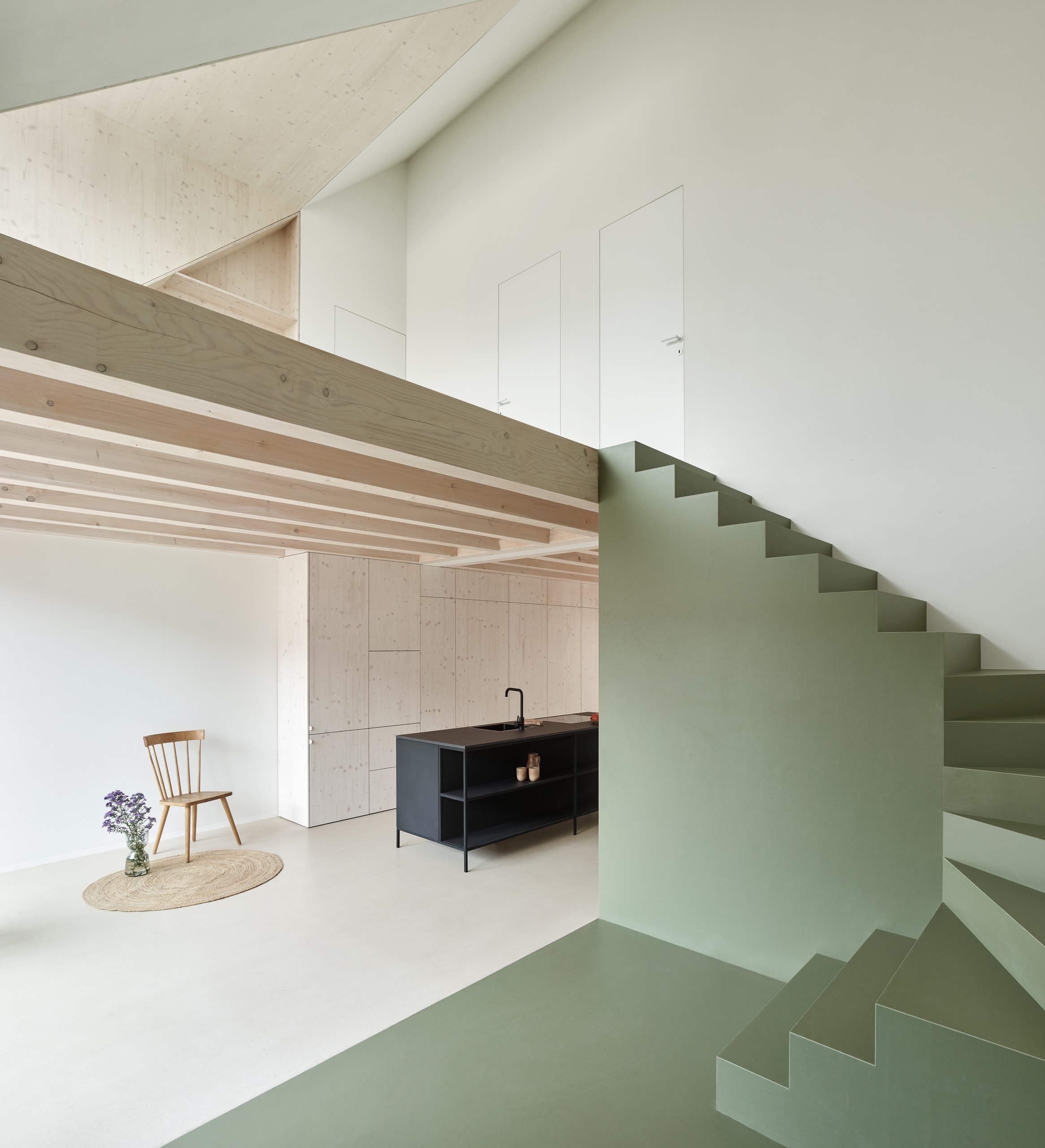 RÖFIX präsentiert eine Wohnung das Referenzprojekt Stadthaus Lederergasse mit Dachschräge, Holzzwischendecke, modernen Treppen, flächenbündigen Türen und deckenhohem Wandverbau in der Küche.
