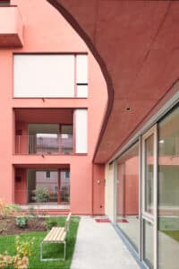 RÖFIX präsentiert die Außenansicht eines Mehrparteienhauses mit Satteldach, orangen Balkongeländern aus Metall und orangem Außenputz.