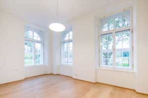 RÖFIX zeigt den Innenraum eines renovierten Gebäudes mit weißem Anstrich, Holzboden und Kassettenfenstern.
