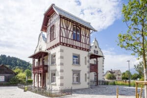 RÖFIX zeigt die Außenansicht einer renovierten Villa mit Satteldach, Fachwerkaufbau und weißem Außenputz mit Verziehrungen.