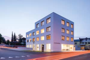 RÖFIX präsentiert die Außenansicht des Referenzprojekts Haus am Winzersteig mit Flachdach und weißem Außenputz bei Abendstimmung.