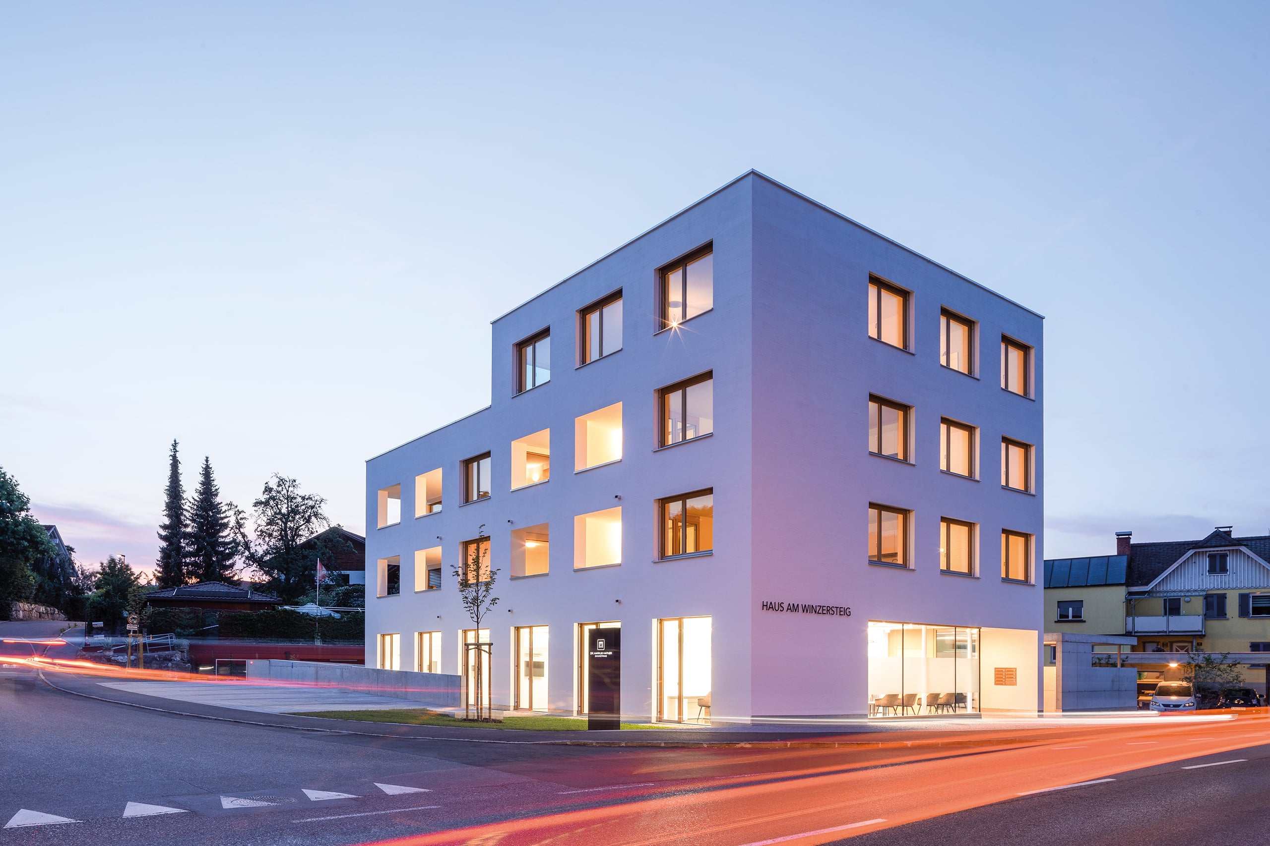 RÖFIX präsentiert die Außenansicht des Referenzprojekts Haus am Winzersteig mit Flachdach und weißem Außenputz bei Abendstimmung.