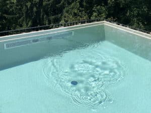 Eine Nahaufnahme einer Infinity‑Poolkante, wo das Wasser scheinbar ins Unendliche fließt von Ruha Stelzmüller.