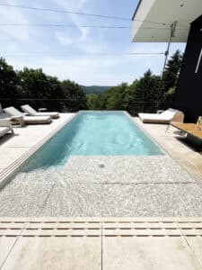 Eine Dachterrasse mit Pool, der zwei unterschiedliche Wassertiefen aufweist, von Ruha  Stelzmüller.