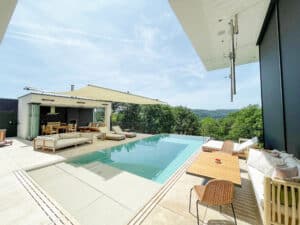 Ein Poolbereich mit stilvollen Sonnensegeln über einer Dachterrasse von Ruha Stelzmüller.