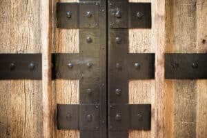 Nahaufnahme eines naturbelassenen Holztors mit rustikalen, mittelalterlich wirkenden schwarzen Eisenbeschlägen von SILBER Fensterbau.