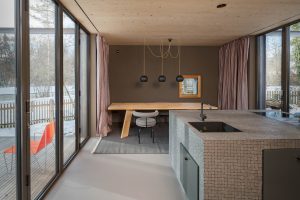 Solarlux zeigt modernes Holzhaus mit geschlossenen Faltschiebetüren mit dunkelgrauem Rahmen mit Blick auf den Garten.