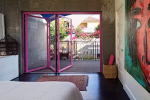 Moderne Wohnung mit Sichtbetonwänden und einem Balkon mit Glas-Faltwand SL45 in einem markanten pinken Rahmen von SOLARLUX.