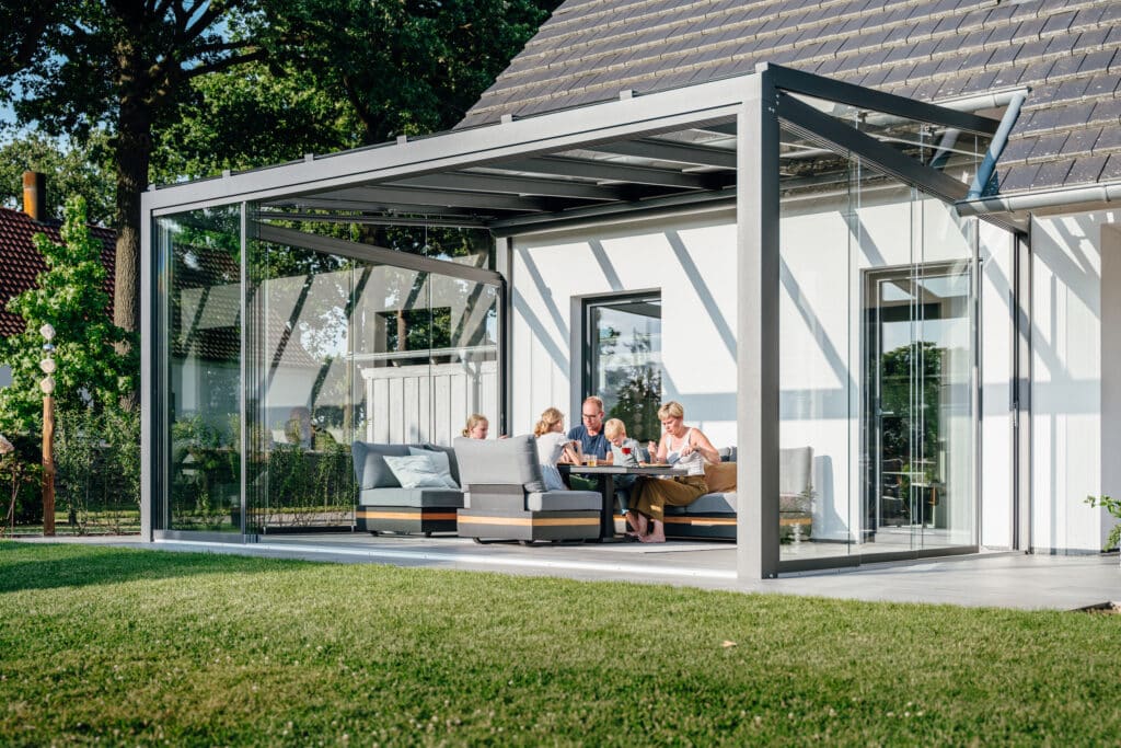 Ein stilvoll eingerichtetes Glashaus von Solarlux macht die Terrasse zu einem Essbereich und Wohnzimmer - für ein modernes Outdoor-Wohngefühl.