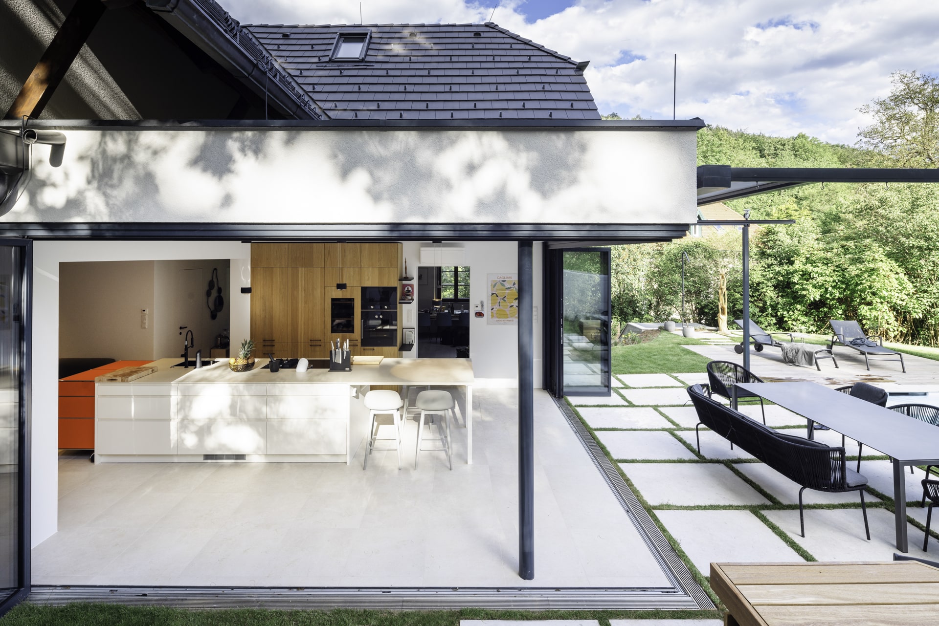 Solarlux präsentiert ein saniertes Einfamilienhaus mit großer offener Küche, Essbereich und Glasfaltwänden an zwei Seiten, die zur Terrasse hin geöffnet werden können.