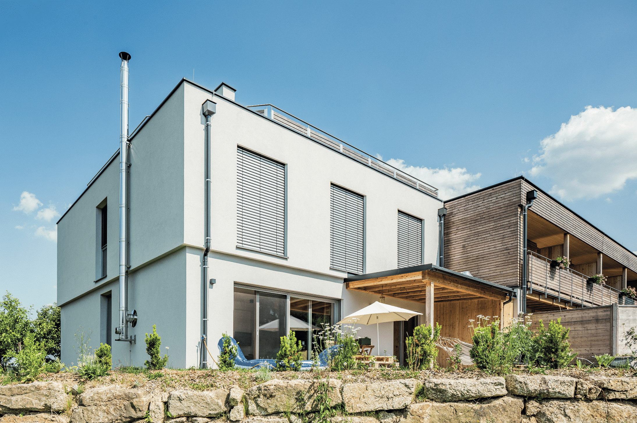 Modernes Einfamilienhaus mit Pool, Outdoordusche, Balkon mit Glasgeländer, geflieste Terrasse mit Gartenmöbel von SynthesaGruppe.