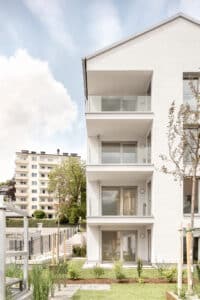 Synthesagruppe zeigt ein Mehrparteienhaus mit Satteldach, Balkonen und weißer Fassade.