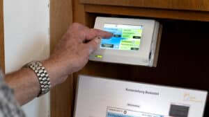 Technische Alternative RT zeigt die Handhabung des Displays eines Heizungsreglers mit Touchscreen in einer Kirche.