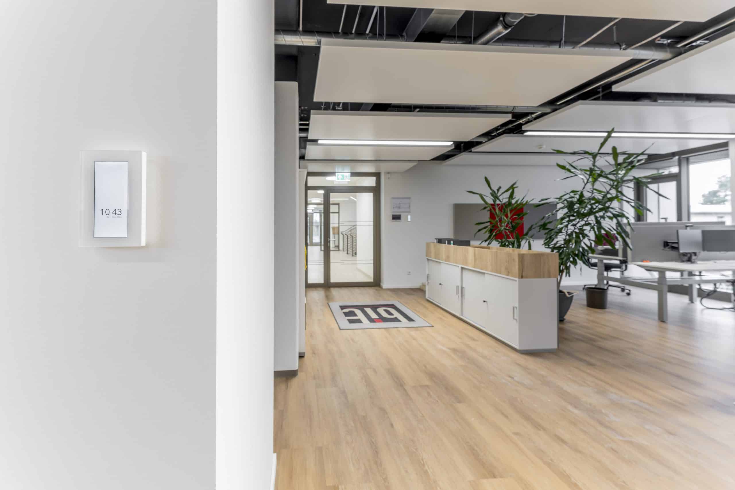 Thermokon zeigt das an der Wand montierte Raumbedienelement eines Großraumbüros mit Display.