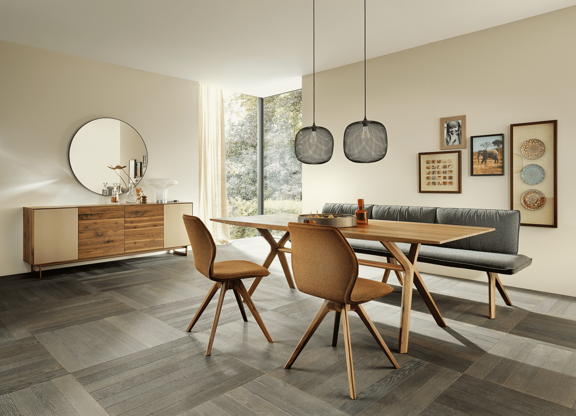 Bauer Tischlerei zeigt ein Esszimmer mit kariertem Boden, einer Essgruppe aus Holz mit grauer Sitzbank und einer Wandkommode mit einem großen, runden Spiegel von Anrei.