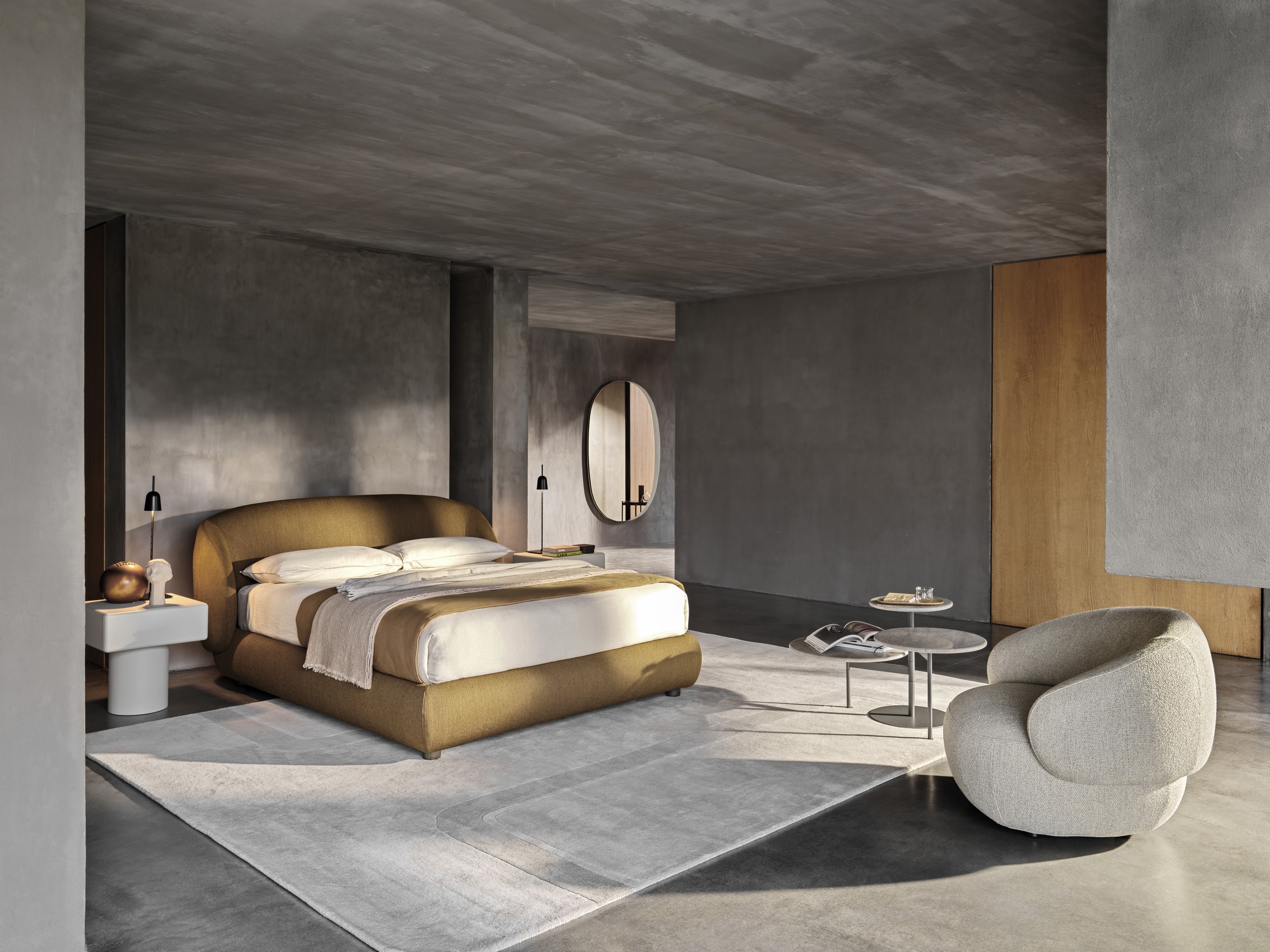 Bauer Tischlerei zeigt Schlafzimmer mit Boxspringbett mit orangem Stoffbezug, Beistelltisch und Sessel mit grauem Stoffbezug und Armlehne von Ditre Italia.
