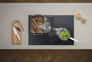 BAUER Tischlerei zeigt das BORA Classic Induktionskochfeld mit integriertem Downdraft-Dunstabzug eingefasst in eine gesprenkelte hellgraue Steinarbeitsplatte.