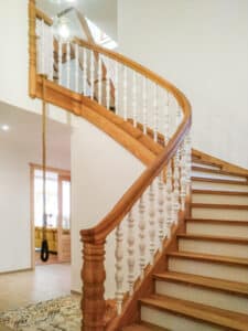 Klassisches gewendeltes Holztreppenhaus mit Auftritt, Handlauf und Wangenelementen aus Vollholz und gedrechstelten Ballustraden in Weiss von Tischlerei Penninger.