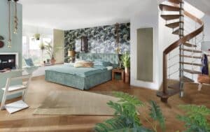 Ein loftartiges Schlafzimmer mit einer Wendeltreppe aus dunklem Holz neben einem Infrarotwandheizkörper von Treppenmeister.