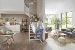 Ein offener Wohnraum im Erdgeschoss mit einer Holztreppe, auf der gerade Möbel transportiert werden von Treppenmeister.