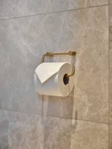 VOLA zeigt einen goldenen Klorollenhalter.