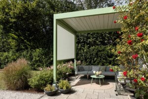 Klassische Villa mit verspieltem Garten und einer Terrasse mit Sitzgruppe unter einer grünen Pergola mit geschlossenem Lamellendach und einer weissen, schattenspendenden Seitenmarkise von Warema.