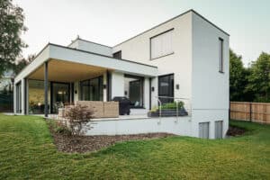 Ein modernes Haus mit überdachter Terrasse und Garten – ein Zuhause von Weissenseer.