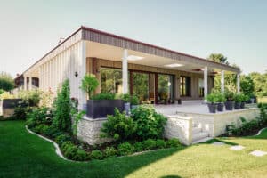 Ein moderner Bungalow mit Flachdach, Holzfassade, Steinfundament, Garten und Terrassenschiebetür von Weissenseer.