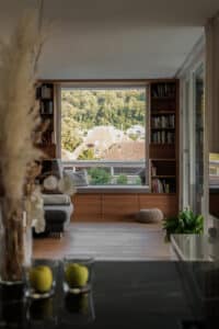Ein heller Wohnraum mit Holz-Sitznische und Ausblick, harmonisch gestaltet von Weissenseer.