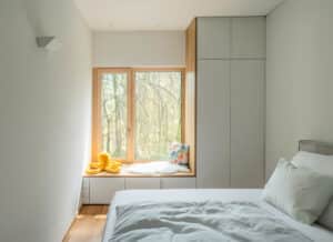 Ein helles Zimmer mit schlichtem Wandverbau und eingelassenem Sitzfenster lädt zu ruhiger Einkehr und kindlicher Geborgenheit in ein Haus von Weissenseer ein.