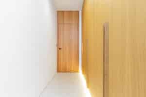 Die moderne deckenbündige Innentür "Rumburk" mit Holzfurnier fügt sich nahtlos in den Vorraum mit passendem Wandverbau ein und schafft ein minimalistisches, elegantes Raumkonzept mit klaren Linien von WIENTÜR91.