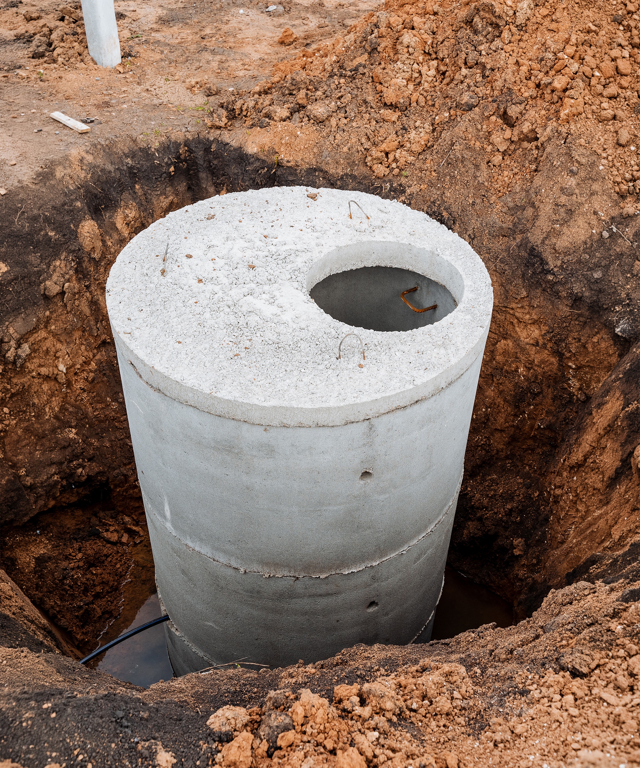 Einbau von Betonringen für die Abwasserleitung im Vorortbereich, Installation einer häuslichen Kläranlage (Senkrgrube) sowie eines runden, in einer Baugrube versenkten Klärbehälters. - KI-generiert