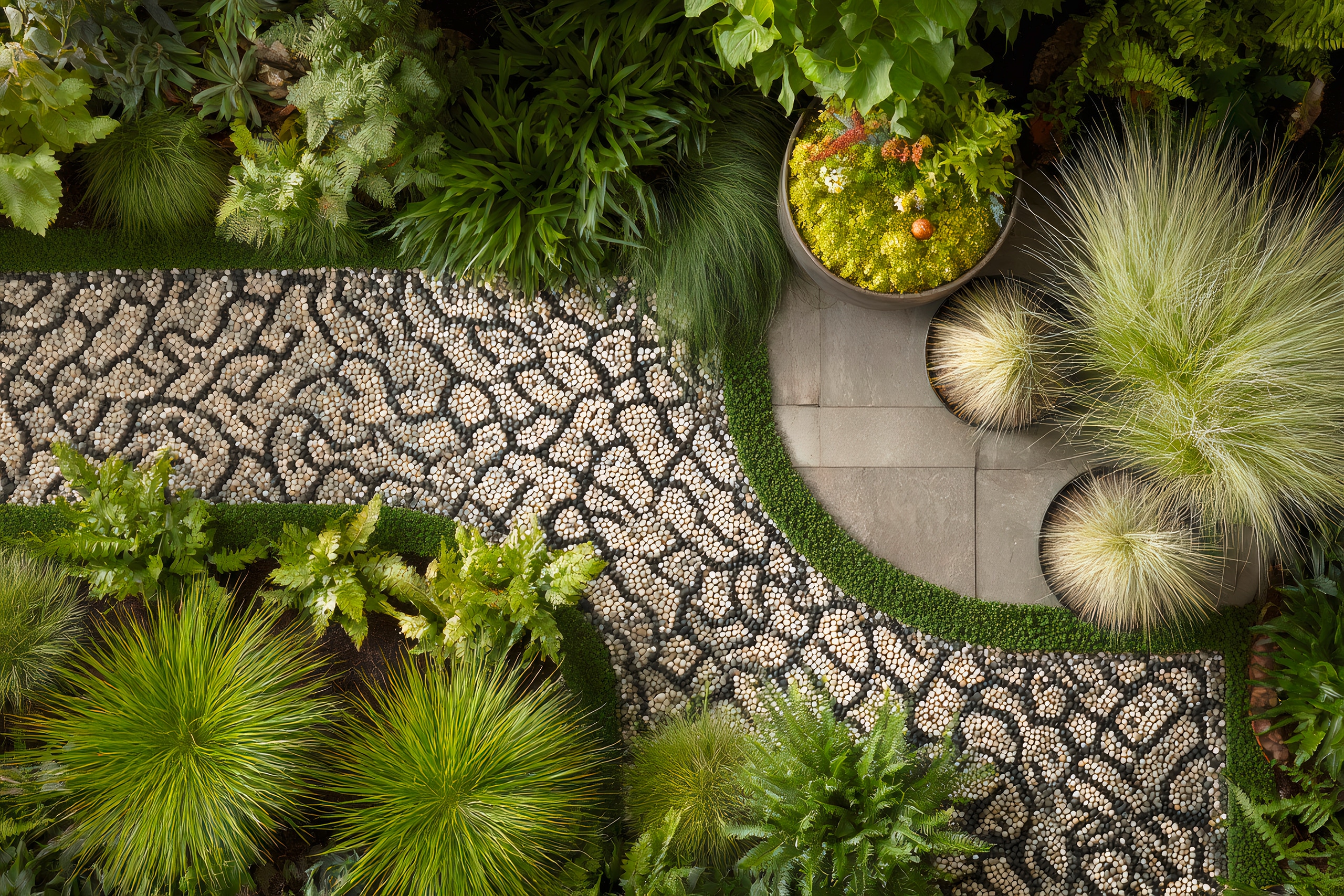 Steinpfad mit ansprechendem, orientalischem Muster schlängelt sich durch einen üppigen grünen Garten und webt eine strukturierte Mosaikoberfläche zwischen grünen Landschaftselementen.