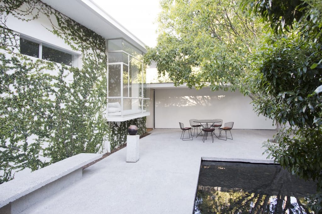 Hinterhof eines modernen Einfamilienhauses mit Terrasse und angrenzendem Teich.