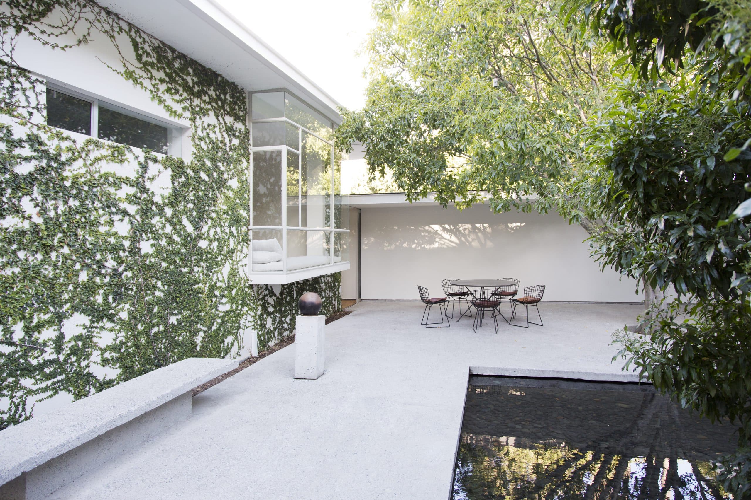 Hinterhof eines modernen Einfamilienhauses mit Terrasse und angrenzendem Teich.