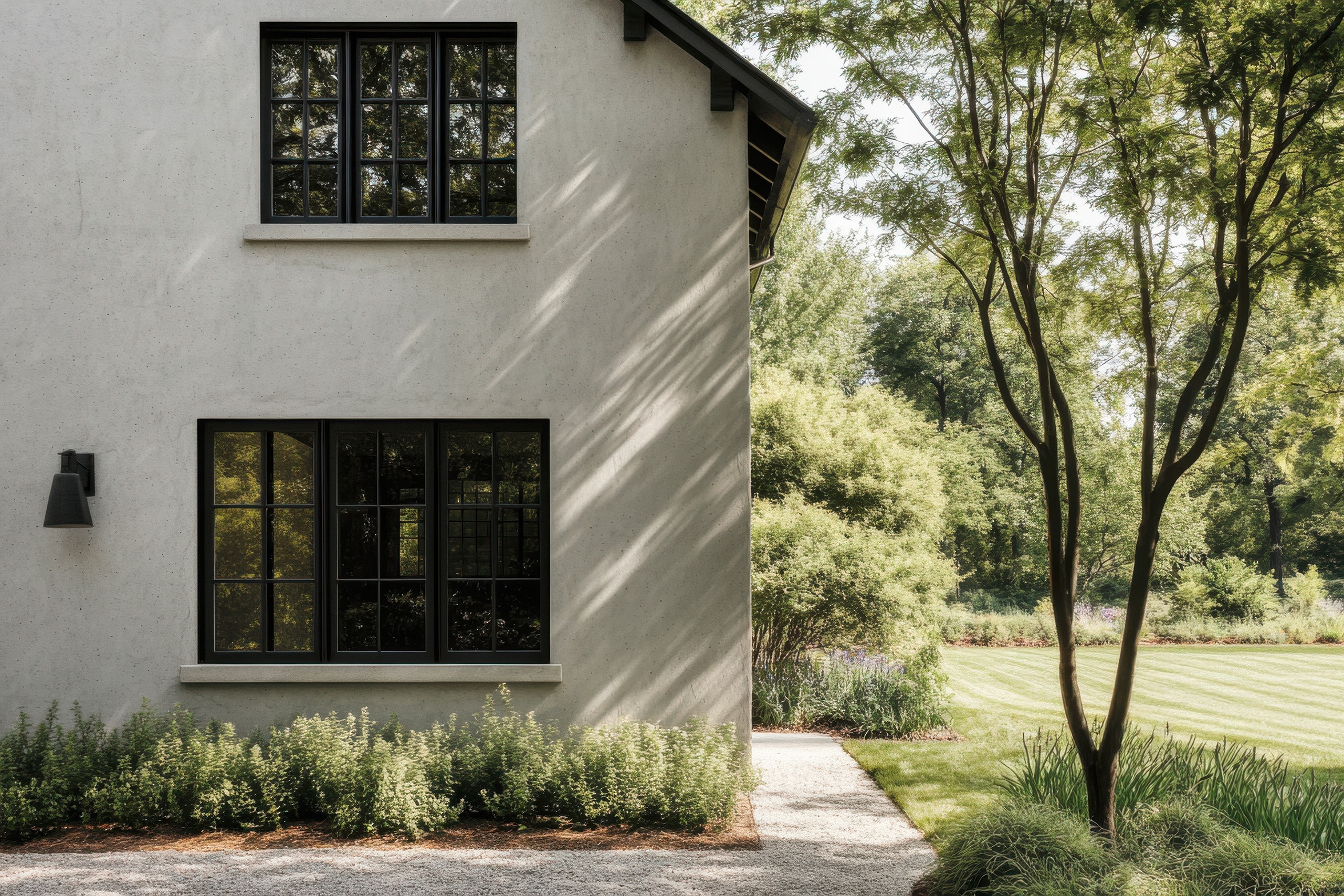 Modernes Haus, umgeben von üppigem Grün in einer ruhigen Außenanlage, in der am späten Nachmittag Sonnenlicht durch die Bäume fällt. Üppiges Grün und moderne Fenster schaffen einen friedlichen Rückzugsort in einer idyllischen Umgebung.