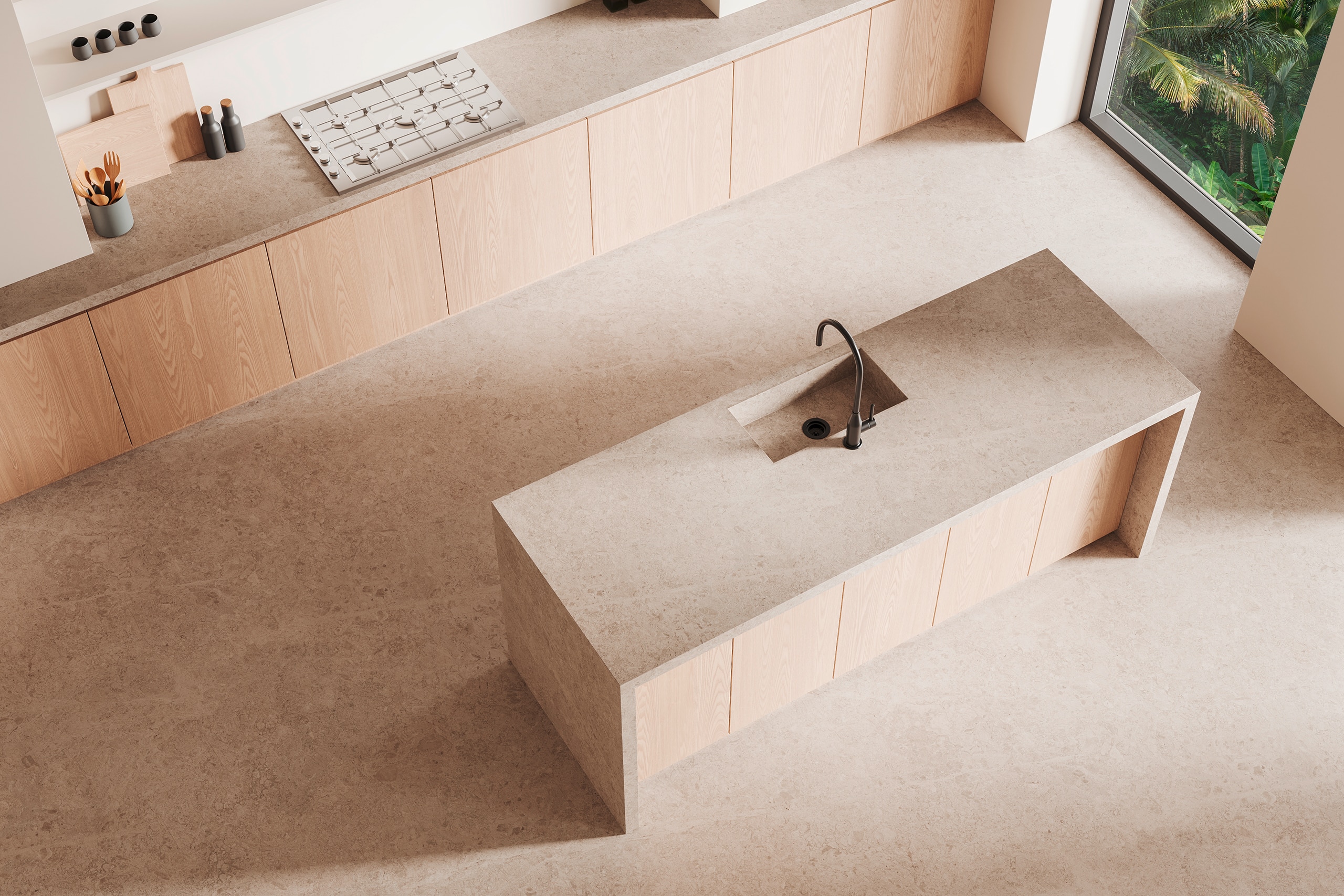 Minimalistisches Kücheninterieur mit beigefarbenen Arbeitsplatten aus Naturstein und dem Bodenbelag aus dem selben Material, einer zentralen Kochinsel mit dunklem, matten Wasserhahn bzw. Armatur und natürlichem Licht.