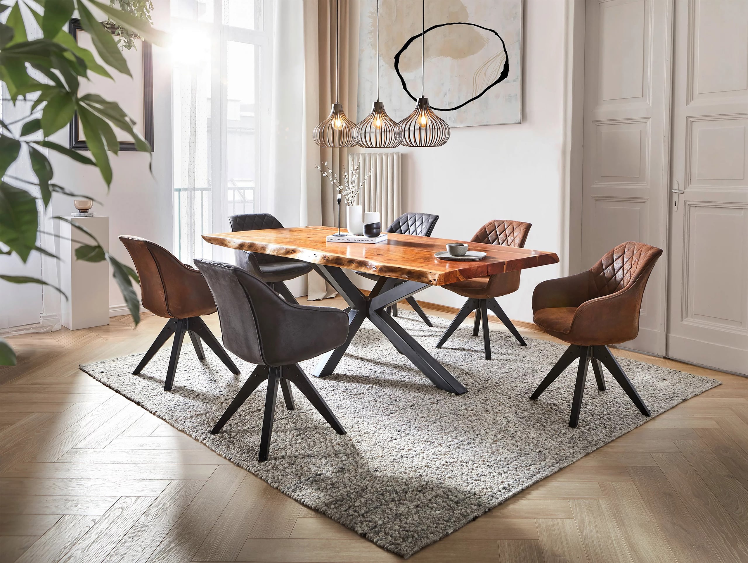 Moderner Essbereich bzw. Esszimmer mit einem Esstisch mit einer massiven Holzplatte mit Naturrandkante, 6 Stühlen in Lederoptik. Der Tisch verfüget über ein schwarzes Gestell aus Metall.