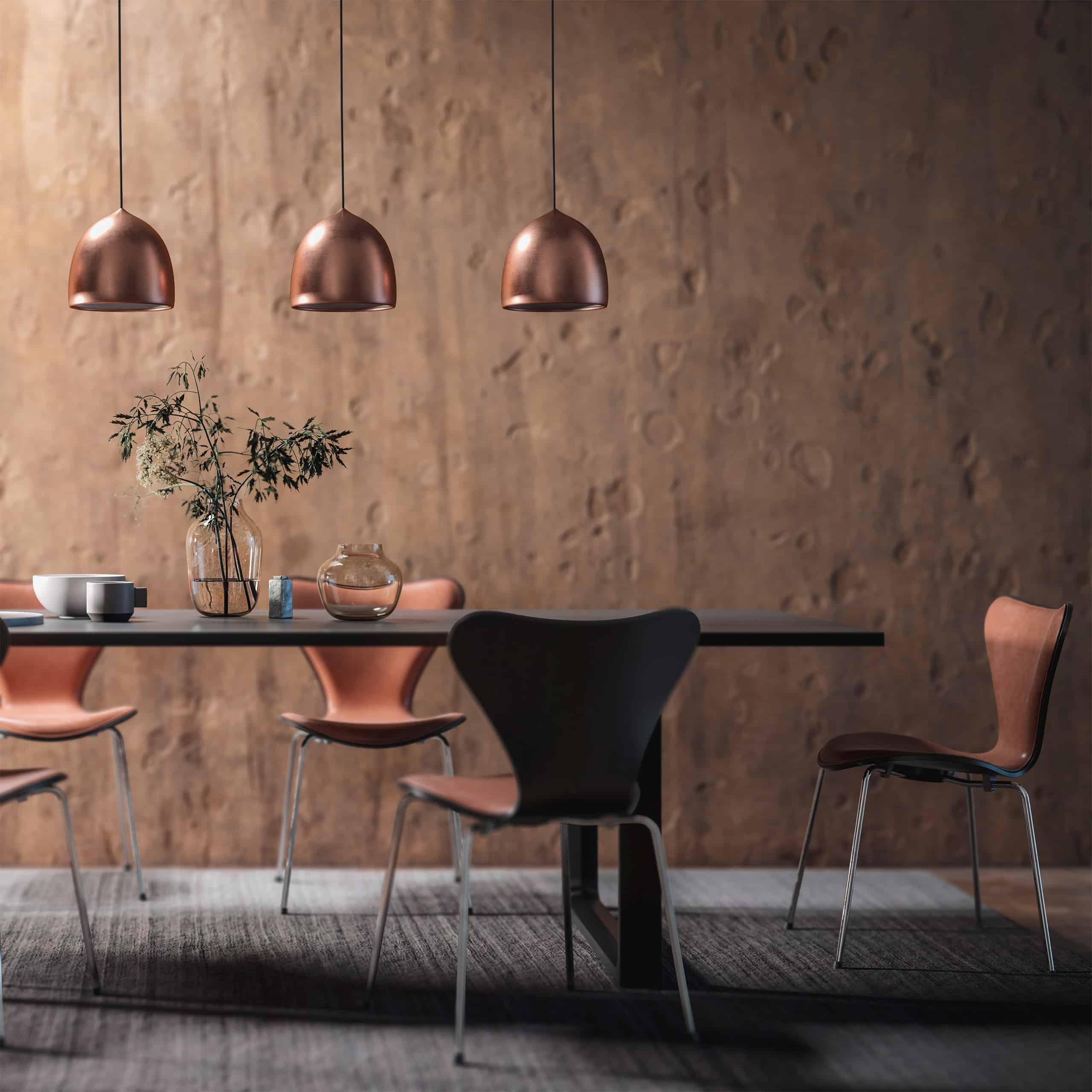 Detailansicht eines Essbereiches in einem Esszimmer mit einem lange, großen Esstisch mehreren Lederstühlen und einer 3-teiligen Deckenleuchte mit bronzefarbenen Leuchten.