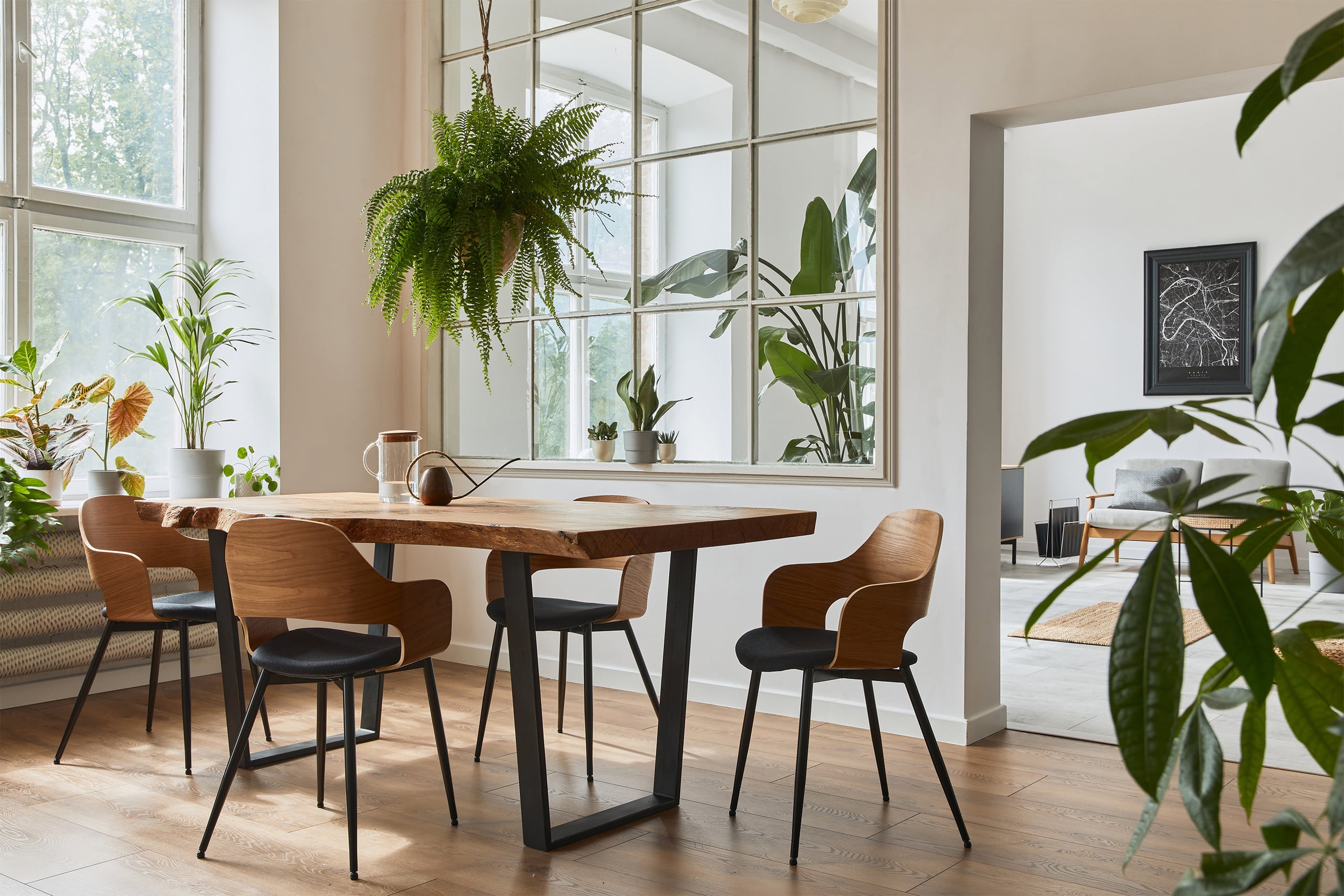 Stilvolles und gemütliches Esszimmer-Interieur (Esszimmer bzw. Essbereich)mit einem handgefertigten Design-Holztisch, Stühlen, Pflanzen, einem Samtsofa, einer Landkarten-Grafik und eleganten Wohnaccessoires im modernen Stil.