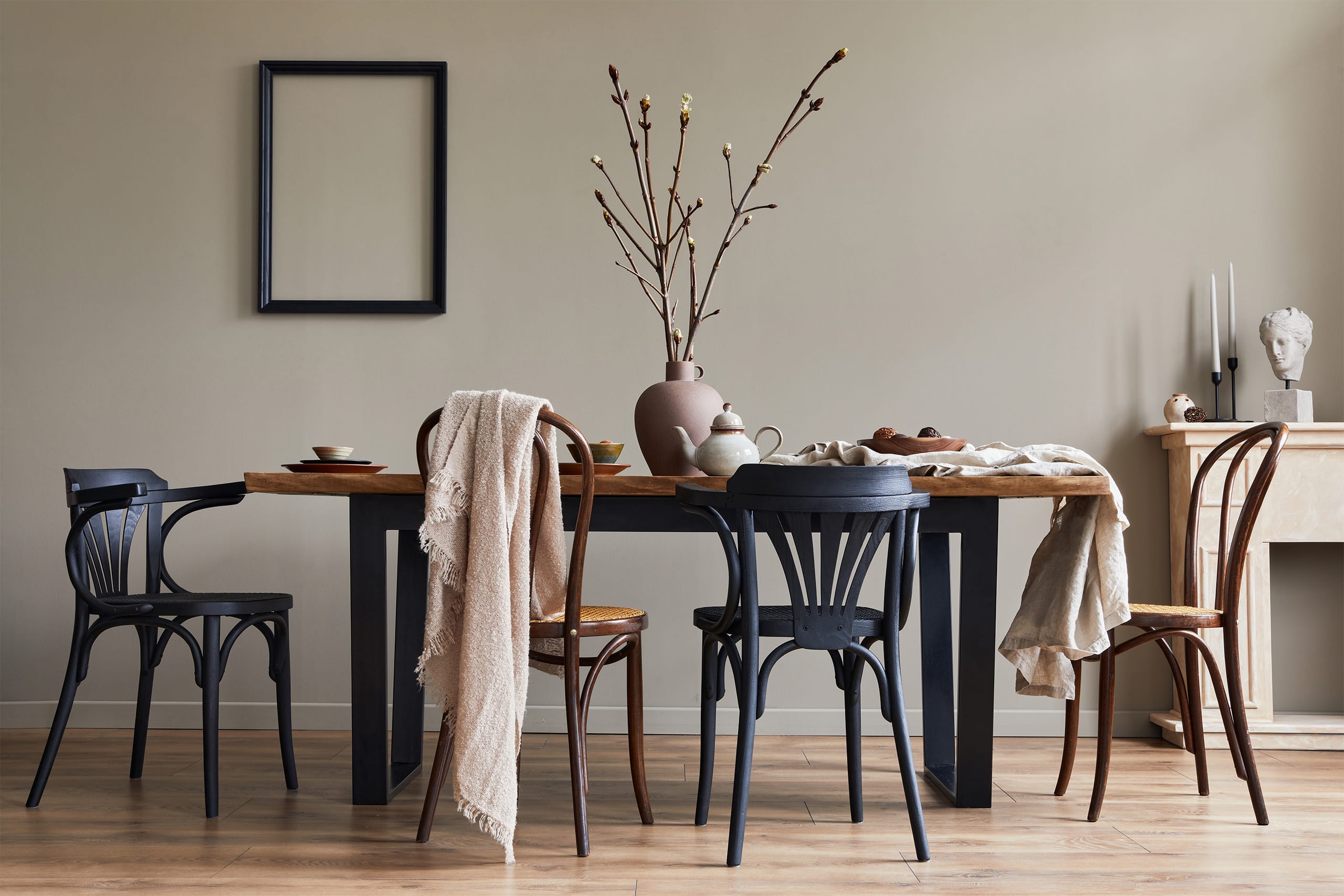 Stilvolles, rustikales Esszimmer. bzw. Essbereich mit Walnussholztisch, royalblauen Retro-Stühlen, Dekoration, Kamin, Trockenblumen, Kerzenständer, Bilderrahmen-Attrappe und Teppich im minimalistischen Wohnstil.