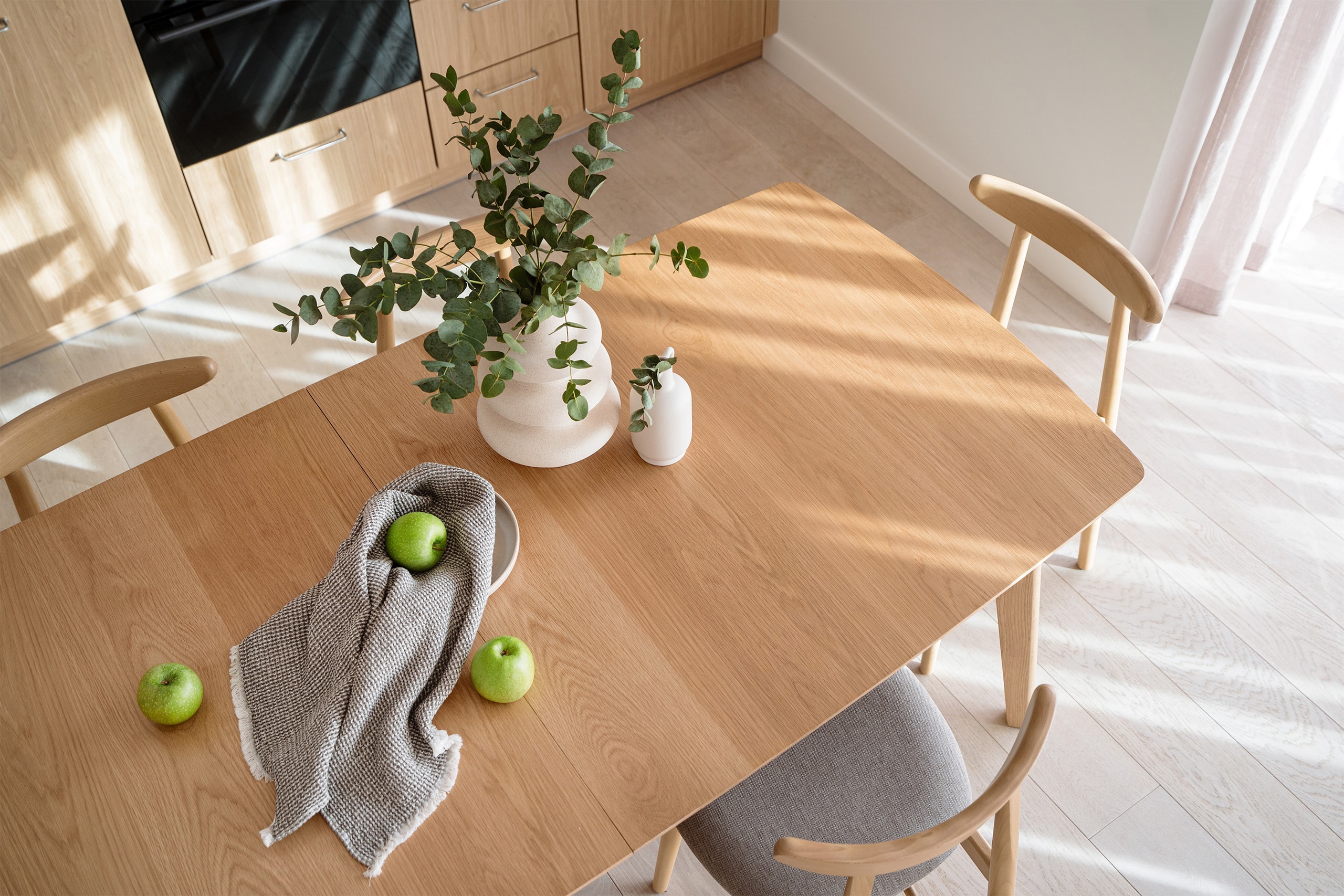 Detailansicht einer moderne Tischplatte aus hellem Holz aus der Vogelperspektive in einer modernen Küche eines hellen Raumes.